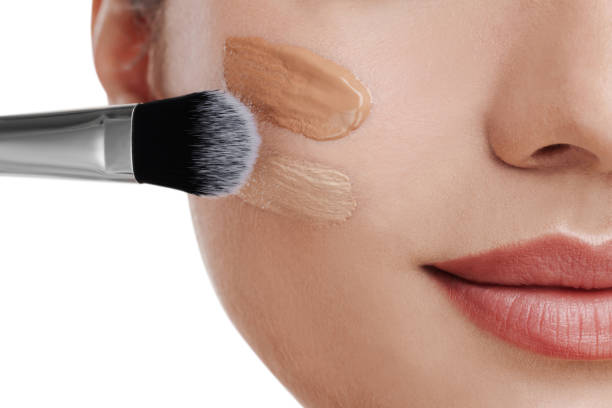 istock Woman applying foundation on face with brush against white background, closeup 1754761045
