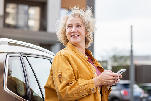 A mid adult modern woman paying car parking with a mobile app on her cell phone