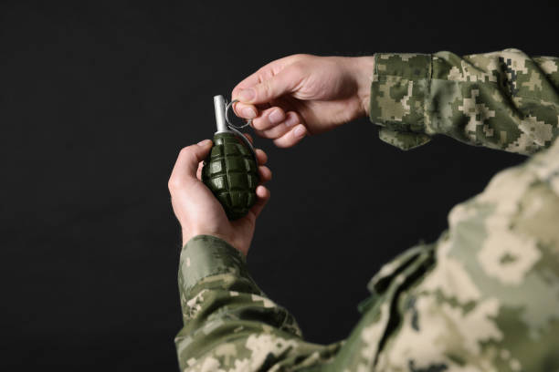 soldat zieht sicherheitsnadel aus handgranate auf schwarzem hintergrund, nahaufnahme. wehrdienst - hand grenade stock-fotos und bilder
