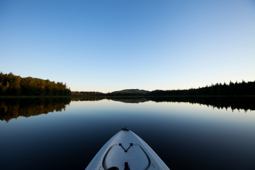 Kayaking on a glassy lake in Maine early in the morning.