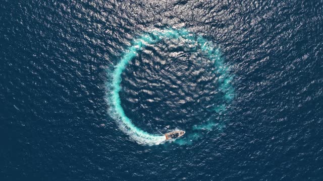 Amazing aerial view of man driving a personal watercraft in the ocean creating a straight down circular pattern, nature background, Water color and beautiful bright Clear turquoise Adventure day on tropical beach Spinning speed boat, summer background