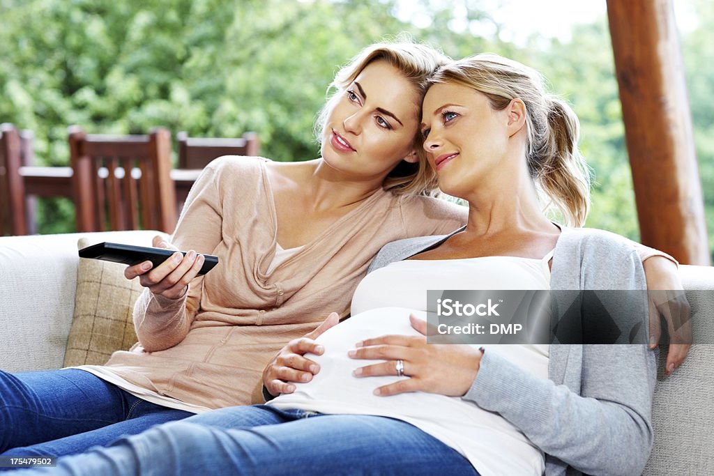 Donna incinta con il suo amico mentre guardi la TV - Foto stock royalty-free di Incinta