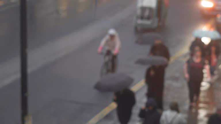 Crowd of people on the busy  street  under umbrella in rainy day,through the window view