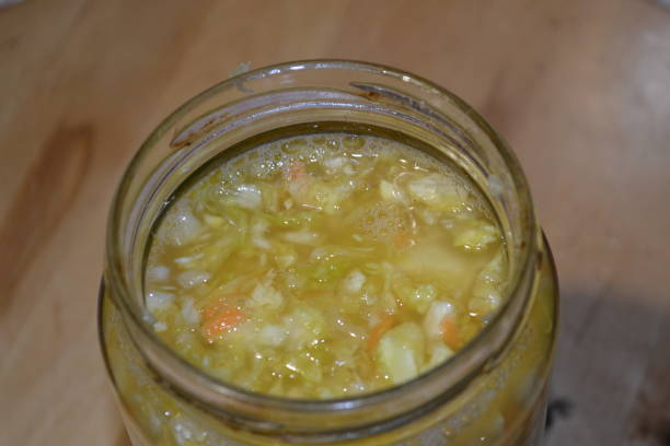 Sauerkraut in a glass jar on wodden brown background. Close-up top view of very juicy chopped fresh cabbage mixed with carrots already salted and fermented and so called sauerkraut in a glass jar. This delicious food is ready to eat and can be used for great quantity of different recipes. Recipe of sauerkraut cooking at home. Fresh vegan food preparation. probiotic pattern stock pictures, royalty-free photos & images