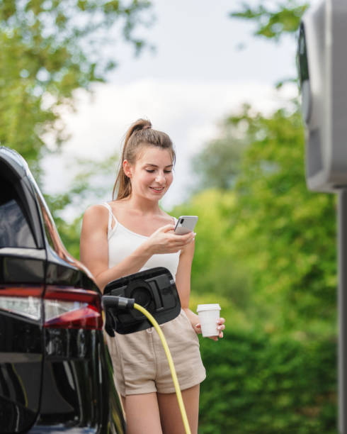 istock Girl plugging a charger into an electric car and using a smartphone 1754813506