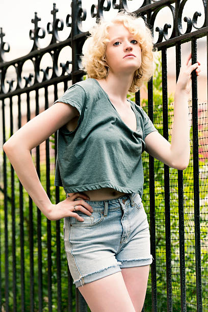 Fashion: funky young woman by the fence