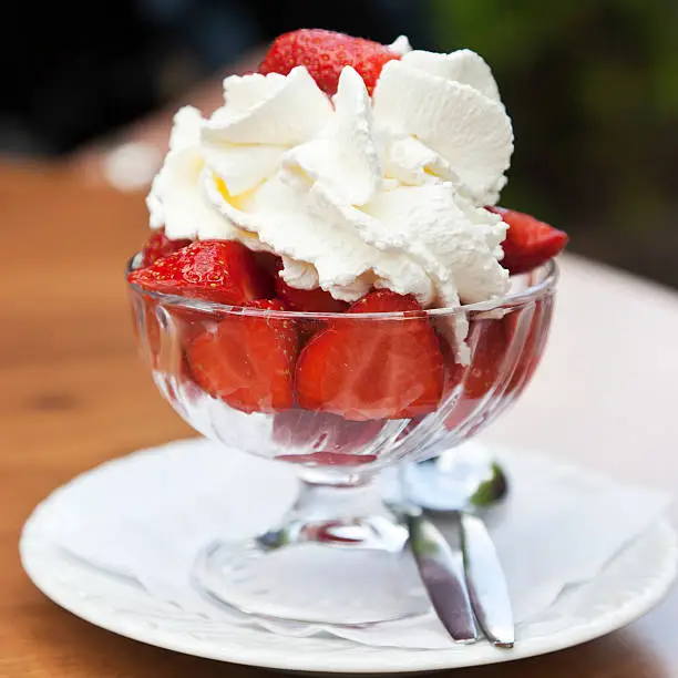 Photo of Bowl of fresh strawberries with whipped cream on top