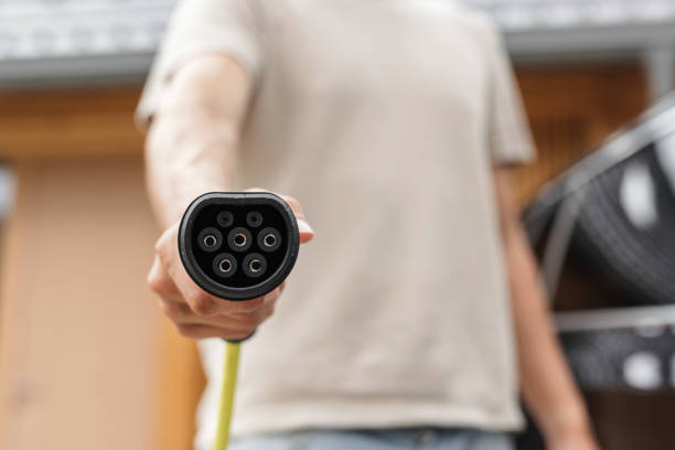 Man plugging a charger in an electric car at home