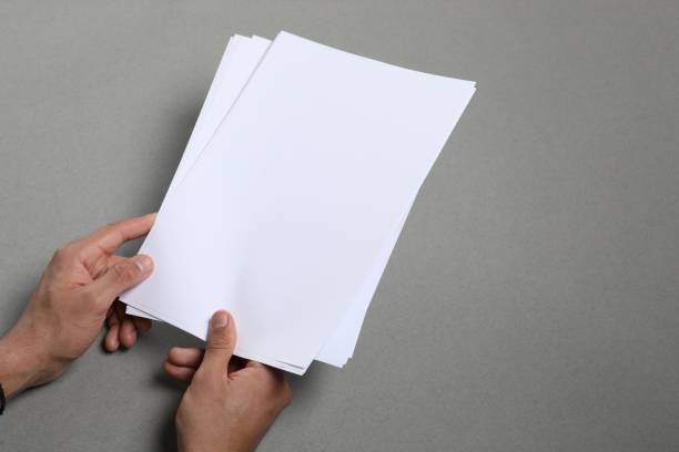 istock Man holding sheets of paper on grey background, closeup. Mockup for design 1754819470