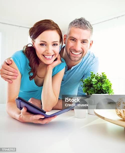 Happy Adult Couple With Ereader At Home Stock Photo - Download Image Now - 20-24 Years, 30-34 Years, Adult