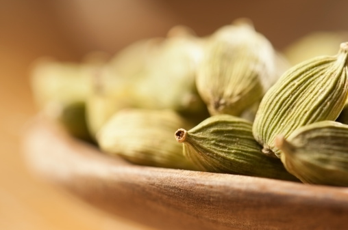 Cardamom pods in a small wooden bowl