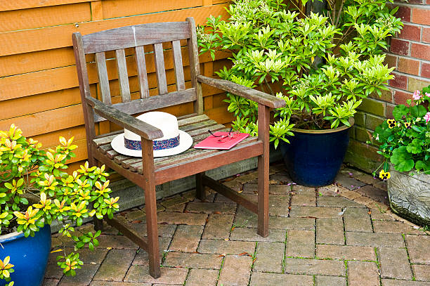 Garden chair with sun hat, book and spectacles in a relaxing corner of the yard.