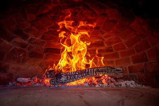 interior view of a Wood Burning Oven with a Strong flame coming out of the wooden log