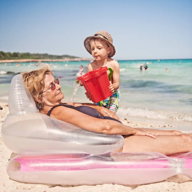 Beach fun with sleeping granny Little boy making a suprise for granny that she will probably not entirely like. bucket photos stock pictures, royalty-free photos & images