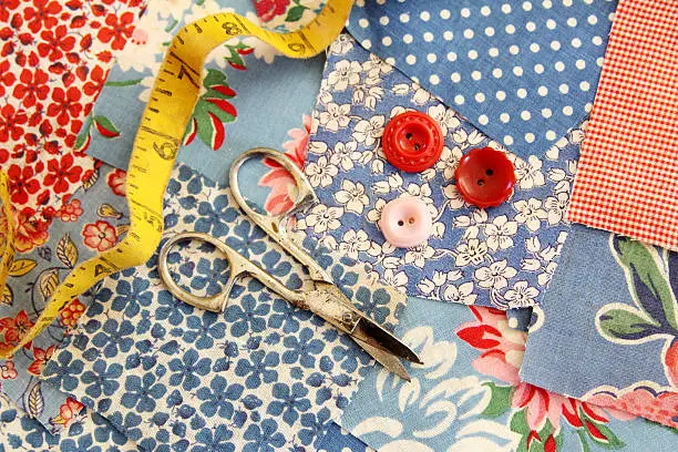 "Antique fabric from the 1950's is photographed, along with an old tape measure, scissors and buttons."