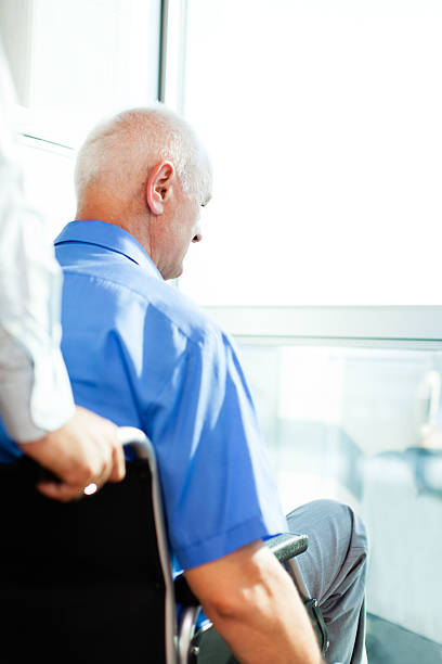 istock Senior man in a wheelchair looking out through window 175483893
