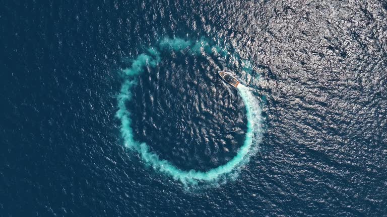 Amazing aerial view of man driving a personal watercraft in the ocean creating a straight down circular pattern, nature background, Water color and beautiful bright Clear turquoise Adventure day on tropical beach Spinning speed boat, summer background