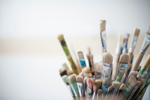 Close up of a series of used brushes in an artist's studio.