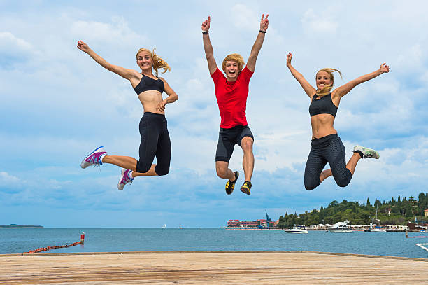 Three attractive athletes jumping by the sea