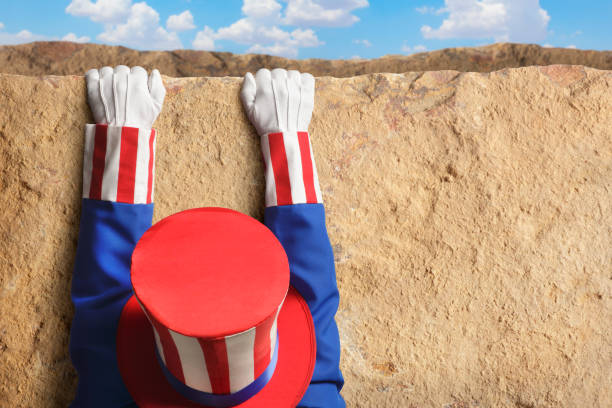 Fiscal Cliff Uncle Sam hanging for dear life from a cliff.To see more Uncle Sam related images click on the link below: uncle sam broke stock pictures, royalty-free photos & images