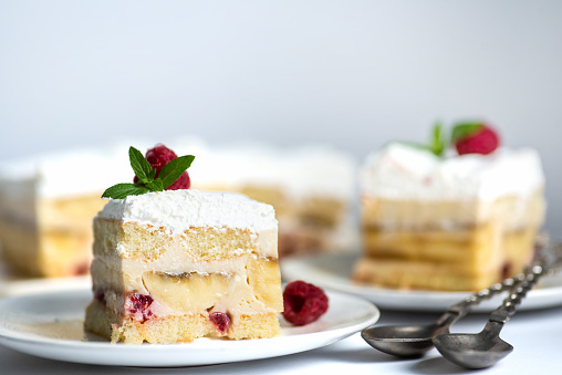 Creamy refreshing fruit cake with biscuits, vanilla cream, bananas and raspberries, decorated with white whipped cream. Served in cake trays