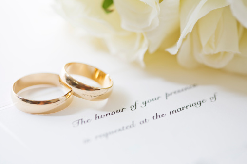 Wedding rings with a wedding invitation and bouquet