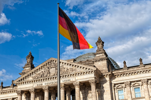 The German flag flies proudly in front of the German Parliament Reichstag building in Berlin on a summer day.
