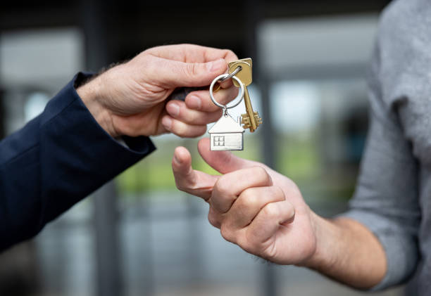 Close-up on a real estate agent giving a man the keys of his new house Close-up on a real estate agent giving a man the keys of his new house - home ownership concepts house and key stock pictures, royalty-free photos & images