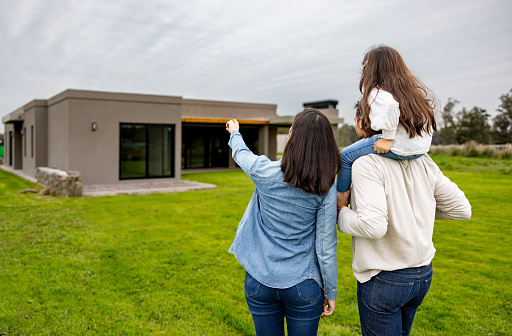 Rear view of a loving family outdoors looking at a house for sale - lifestyle concepts
