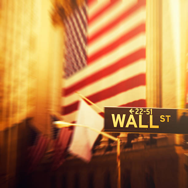 Wall Street sign with the blurred flags of the stock exchange as background. October 2017