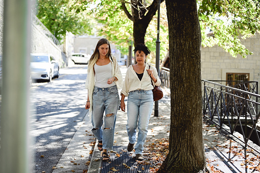 two young women students walking on a city street after lessons.