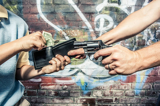 Robber Stealing Wallet From a Man With Gun Two people fight over wallet and money. One person has a knife. Brick wall and graffiti as background. Gun is a .38 special revolver. wallet gun stock pictures, royalty-free photos & images