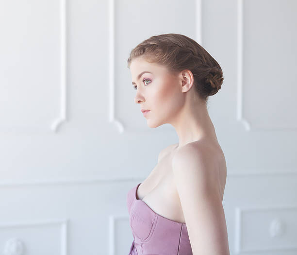 Young woman in white interior Portrait pf young beautiful woman standing in white interior. Professional make-up and hairstyle. braided buns stock pictures, royalty-free photos & images