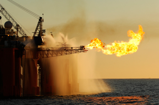 An ocean-based oil rig burning LNG as part of its exploration activities.  Ocean water spraying from the rig provides a heat shield and cools the rig and other equipment.