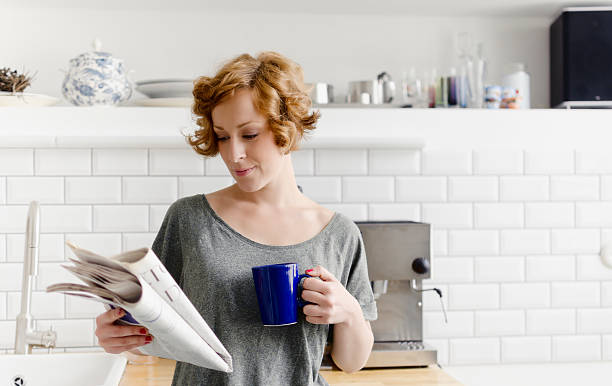 istock Young woman with coffee and newspaper 175490278