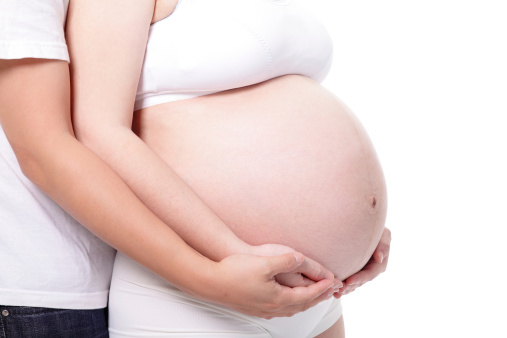 Close-up of pregnant woman grabbing her tummy with copy-space as healthy pregnancy concept