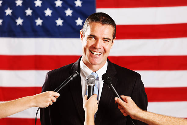 istock Smiling, confident candidate with US flag and microphones 175491135