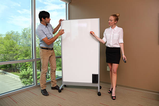 istock caucasian male and female presenters at whiteboard 175491170