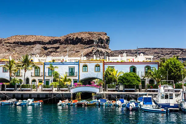 "Colorful waterfront houses at the harbor of Puerto de Mogan with small motor boats, Puerto de Mogan,Gran Canaria Island, Canary Islands, Spain."