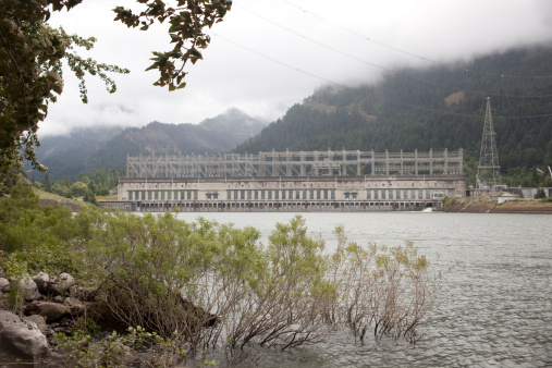 Fog rolls past the Bonneville Dam and Locks which produces electricity while allowing boat traffic upstream and downstream the Columbia River which flows on the Oregon and Washington in the Columbia River Gorge National Scenic Area.