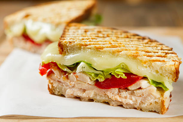 Chicken and salad panini sandwich Freshly cooked panini sandwiches with chicken, tomatoes, romaine lettuce, and mozzarella cheese served on thick sliced rustic bread. panino stock pictures, royalty-free photos & images