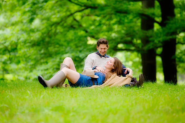 Enjoying Togetherness,Couple Relaxing in Grass Couple lying together in the grass, enjoying their togetherness. women lying down grass wood stock pictures, royalty-free photos & images