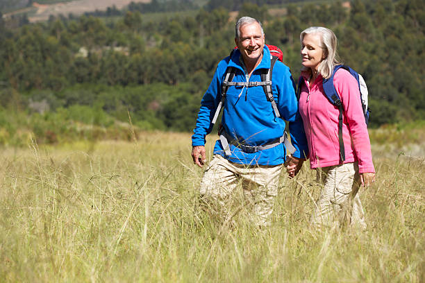 istock Senior couple hiking through a field wearing backpacks 175492589