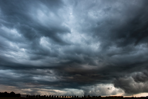 Sinister skyscape above tiny silhouette of treesPLEASE SEE ALSO: