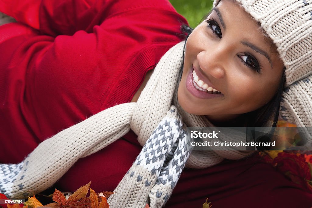 Mujer sonriente que descansan en Hojas otoñales - Foto de stock de 20-24 años libre de derechos