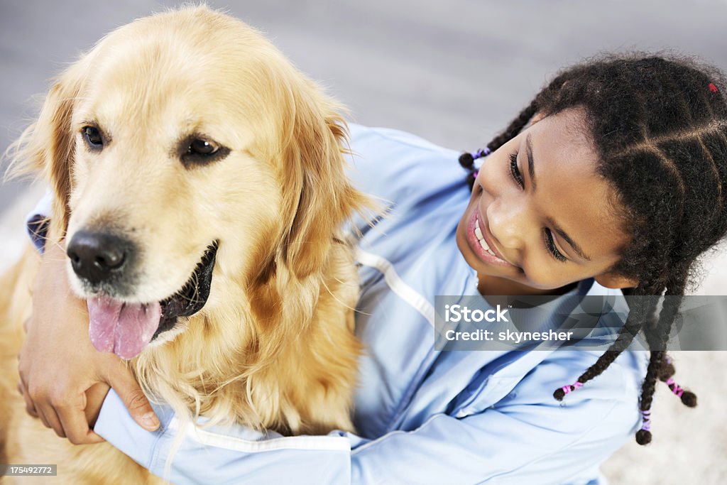 Girl with her dog Portrait of an African American girl embracing her golden retriever dog. Child Stock Photo