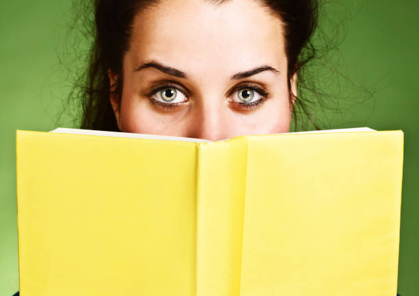 istock Pretty brunette almost obscured by yellow book she holds 175492956