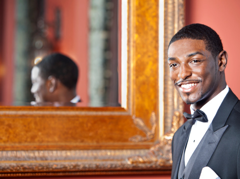 Young Afro American in tuxedo in front of mirror