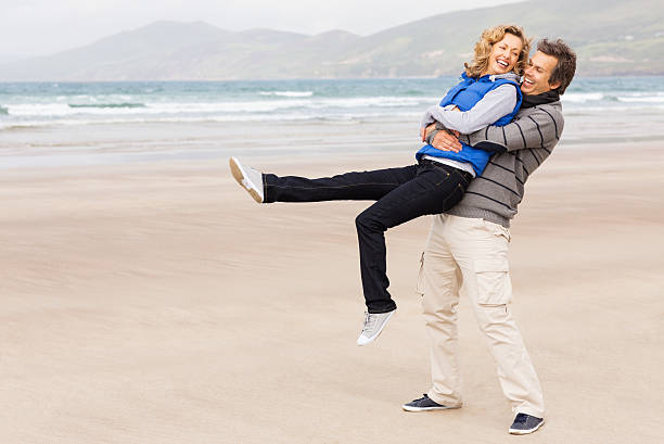 istock Happy Man Lifting Woman On Beach 175494506