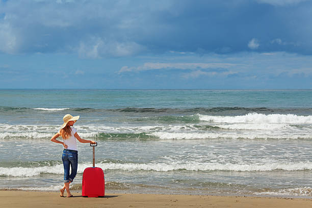 istock girl standing by the sea with suitcase 175494737